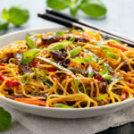 asian recipe of stir fry noodles with beef and vegetable in white bowl
