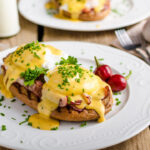 Eggs Benedict with little salad, milk and fresh herbs