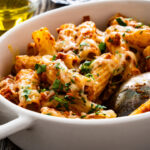 Noodle casserole with minced meat, mozzarella cheese and vegetables on wooden table