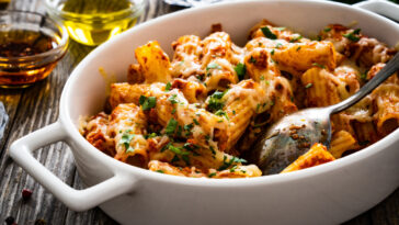Noodle casserole with minced meat, mozzarella cheese and vegetables on wooden table