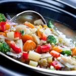 Vegetable soup, slow-cooked in a crock pot, ready to serve.
