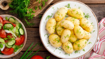 Boiled new potato with fresh dill on wooden background