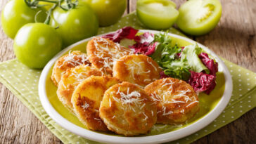 fried green tomato with fresh salad close-up on a plate and ingredients on a table