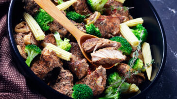 Leftover steak kebabs with vegetables on a black baking dish