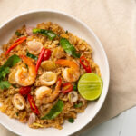 rice cooker dish with shrimp and squid with chilli sauce on white plate.