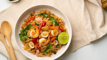 rice cooker dish with shrimp and squid with chilli sauce on white plate.