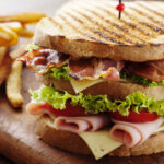 club sandwich paired with french fries on a wood table