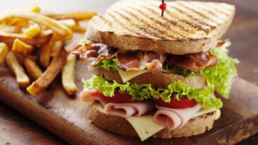 club sandwich paired with french fries on a wood table
