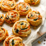 French Savory Puff Pastry Pinwheels stuffed with salmon, cheese and spinach on on baking paper