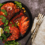 Indian tandoori chicken with naan, lime slices and cilantro, ready to eat. Top view, blank space