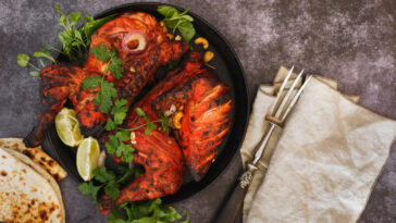 Indian tandoori chicken with naan, lime slices and cilantro, ready to eat. Top view, blank space