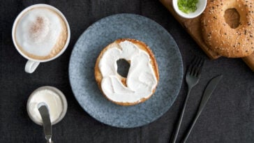 Toasted bagel with cream cheese and cup of coffee for breakfast