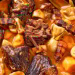 Beef Bourguignon, Beef Burgundy, stew with beef, bacon, carrots, onion bulbs and mushrooms in rich red wine sauce in pot on wooden table