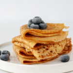 Vegan crepes made from chickpea flour, al purpose gluten free flour and oat milk, with frozen blueberries.