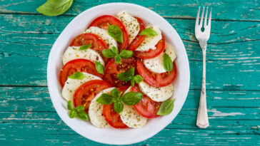 Delicious caprese salad with ripe tomatoes and mozzarella cheese with fresh basil leaves.