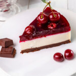 piece of cherry cheesecake on a plate on a white table