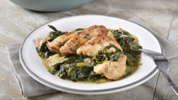Gourmet homemade chicken florentine with a cast iron skillet in the background