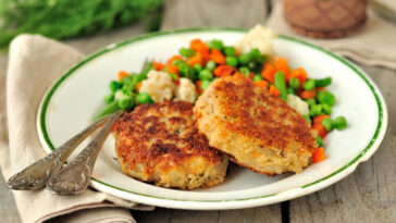 crab cake served with peas and carrots
