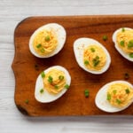 Homemade Deviled Eggs with Chives on a rustic wooden board