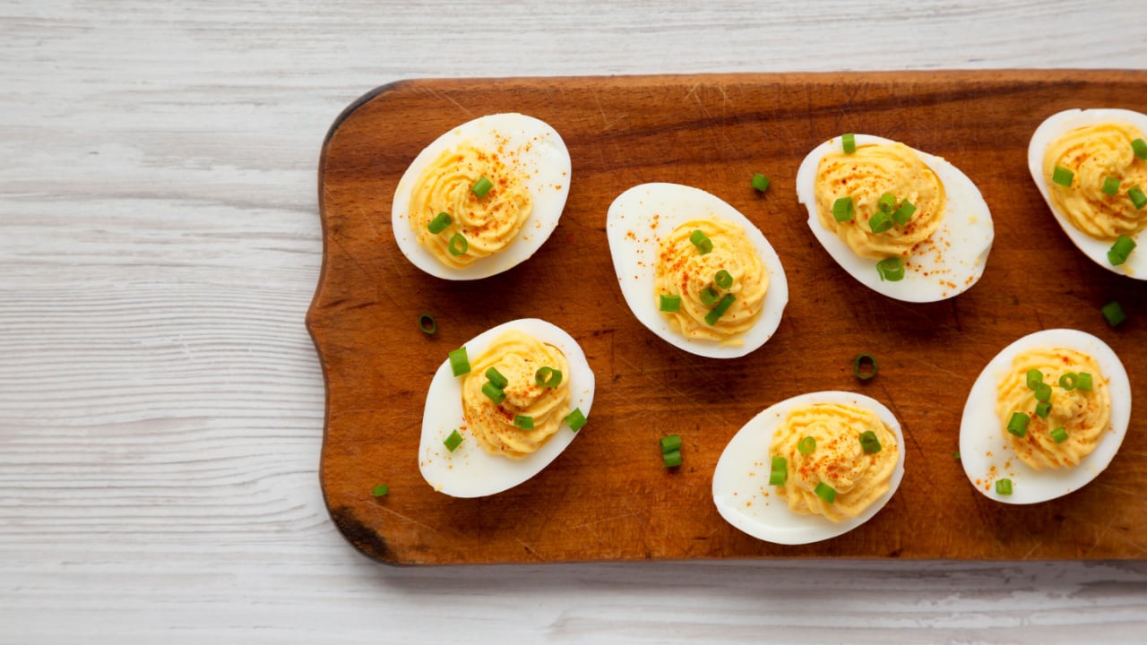 Homemade Deviled Eggs with Chives on a rustic wooden board