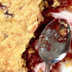Old fashioned dump cake in a white baking dish with serving spoon.