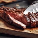 Cutting in slices flank steak on wooden cutting board