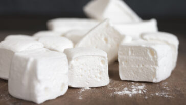 Pile of white homemade marshmallow close-up on wooden cutting board.