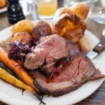 Roast beef on a white plate with roast potatoes