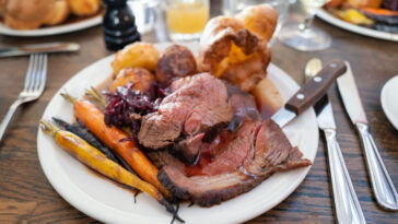 Roast beef on a white plate with roast potatoes