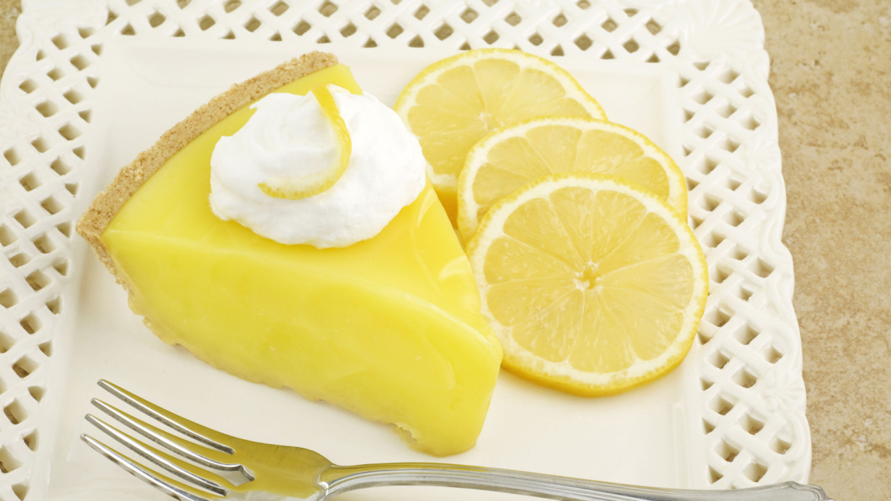 A slice of cool and refreshing lemon icebox pie topped with whipped cream and garnished with sliced lemons
