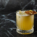 Fruit mixology with mezcal cocktails and dry lime on black marble background.