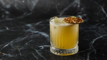 Fruit mixology with mezcal cocktails and dry lime on black marble background.