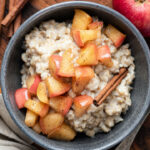 Oatmeal porridge with apple and cinnamon in bowl.
