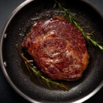 Grilled premium rib eye beef steak in the pan, cooking steak in the kitchen on a dark background