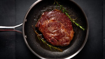 Grilled premium rib eye beef steak in the pan, cooking steak in the kitchen on a dark background