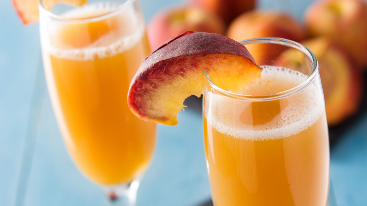 Bellini champagne cocktail in crystal glass on blue wooden table.