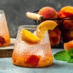 glasses of iced peach cocktail with peach slices.