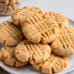 Peanut butter cookies stacked on ceramic plate.