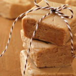 Squares of creamy peanut butter fudge stacked and tied with festive bakers twine for holiday gift giving.