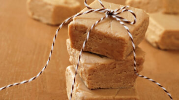 Squares of creamy peanut butter fudge stacked and tied with festive bakers twine for holiday gift giving.