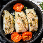 Fried cod fish fillet with spice in a cast iron pan.