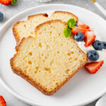 Delicious vanilla pound cake served with fresh berries and whipped cream on a gray concrete background.