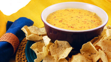 Bowl of warm queso (cheese dip) with a plate of tortilla chips