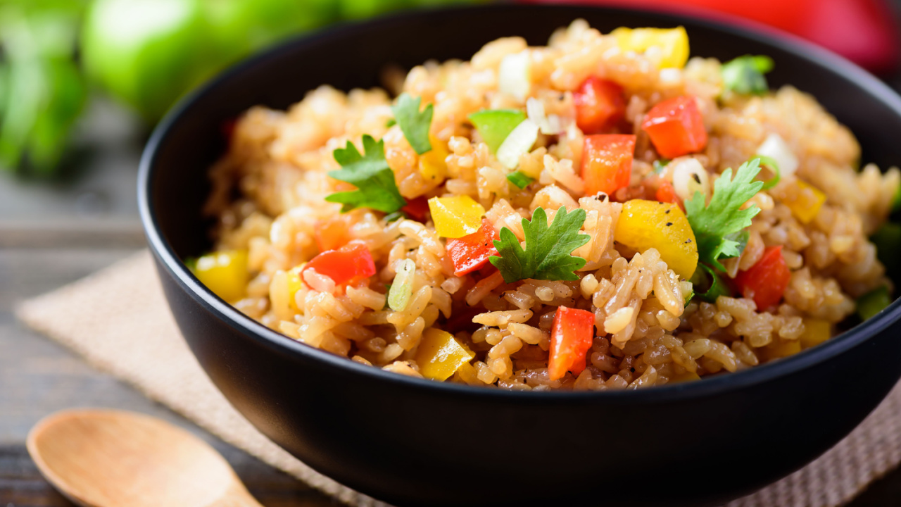 a delicious bowl of fried rice served on with a wooden spoon