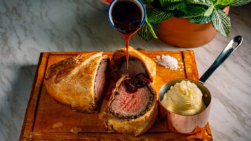 Sliced Beef Wellington with the pouring sauce and the mash potatoes.
