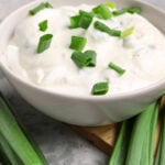 Bowl of tasty sour cream with green onion on table
