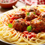 plate of pasta with meatballs on a wooden table