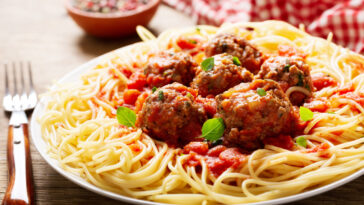 plate of pasta with meatballs on a wooden table