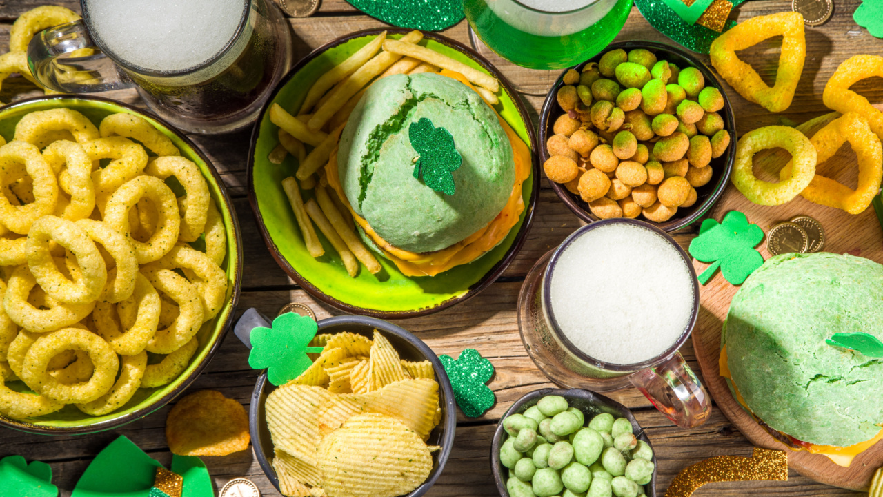 Irish St Patrick`s day beer, ale glasses, snacks, appetizer, green burger, wooden bar table with shamrock, clover, coins, leprechaun hat.
