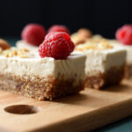 Vegan sugar free dessert. Coconut milk cheesecake bars decorated with raspberries, almonds and coconut flakes